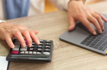Pessoa usando calculadora e computador para entender como calcular aposentadoria especial