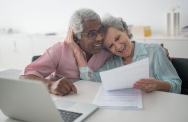 Casal de idosos analisando documentos sobre aposentadoria por tempo de contribuição e idade