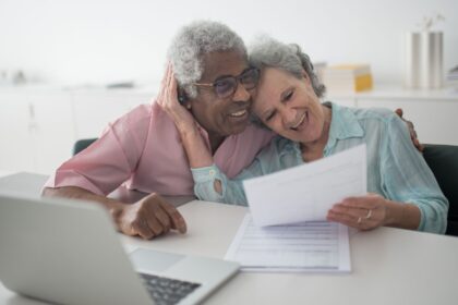 Casal de idosos analisando documentos sobre aposentadoria por tempo de contribuição e idade