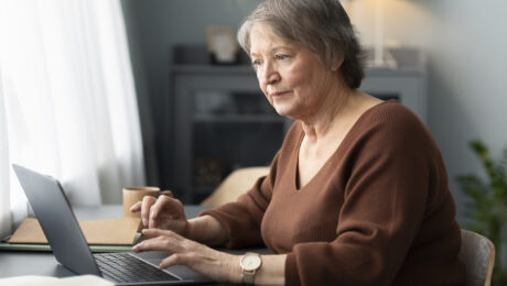 senior-woman-using-laptop-sitting-desk-living-room