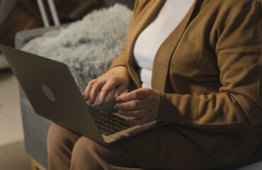 Mulher madura usando notebook em conteúdo sobre aposentadoria híbrida por idade