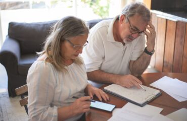 Casal analisando documentos e cálculos em conteúdo sobre como planejar a aposentadoria