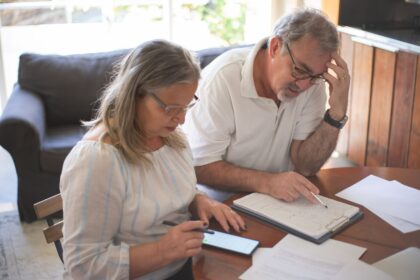 Casal analisando documentos e cálculos em conteúdo sobre como planejar a aposentadoria