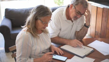 Casal analisando documentos e cálculos em conteúdo sobre como planejar a aposentadoria