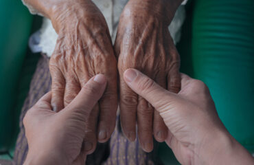 Young woman holding an elderly woman’s hand.