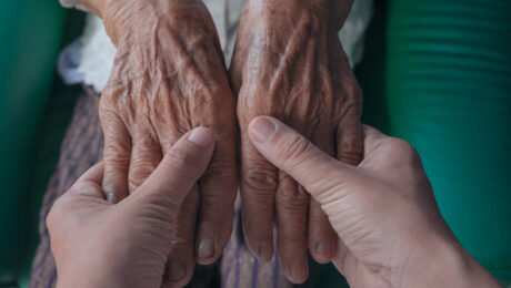 Young woman holding an elderly woman’s hand.