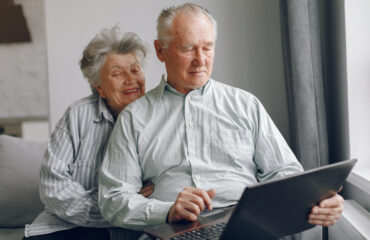 Elegant old couple sitting at home and using a laptop