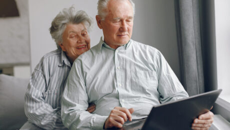Elegant old couple sitting at home and using a laptop