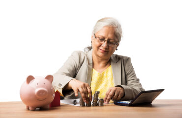 senior Indian or asian business women saving or holding or calculating currency coins. Business, finance and investment concept