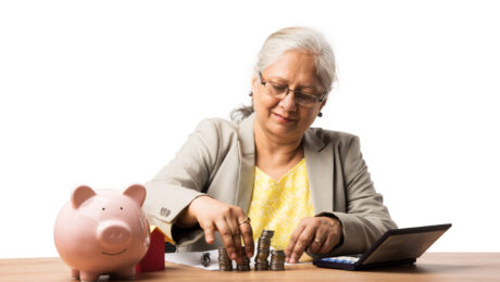 senior Indian or asian business women saving or holding or calculating currency coins. Business, finance and investment concept