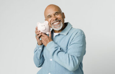 Happy retired man holding his piggy bank