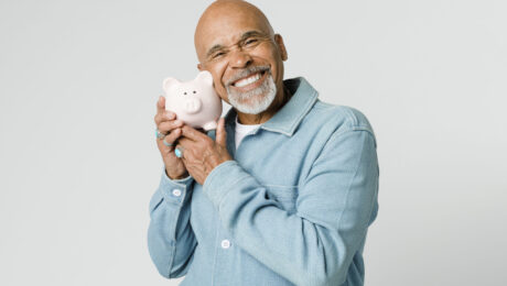 Happy retired man holding his piggy bank