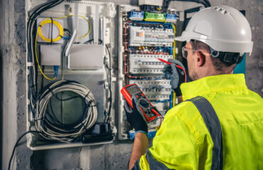 Man, an electrical technician working in a switchboard with fuses.