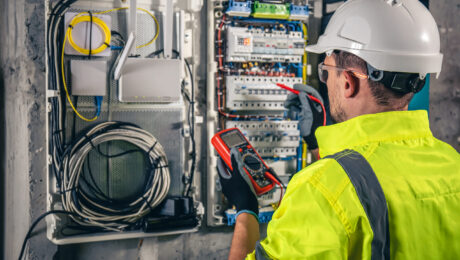 Man, an electrical technician working in a switchboard with fuses.