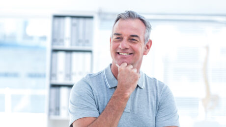 Trabalhador satisfeito ao planejar aposentadoria aos 50 anos. Homem de meia-idade sorrindo em ambiente de escritório, representando a possibilidade de aposentadoria aos 50 anos.