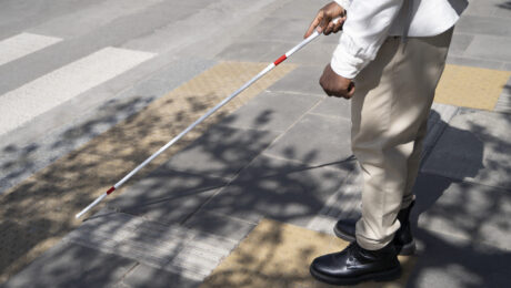 Deficiência visual e direitos previdenciários: saiba como funciona a aposentadoria pela Lei Complementar 142 Pessoa com deficiência visual caminhando com bengala em calçada tátil, simbolizando autonomia e direito à aposentadoria especial