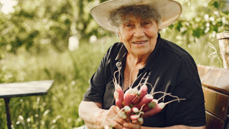 aposentadoria-hibrida-trabalho-rural-urbano Trabalhadora rural idosa sorrindo e segurando vegetais colhidos, representando o direito à aposentadoria híbrida.