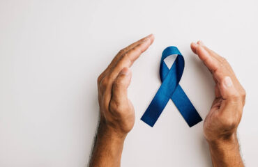 direitos-previdenciarios-pacientes-cancer-de-prostata Mãos em posição de proteção ao redor de um laço azul, símbolo da conscientização sobre o câncer de próstata.