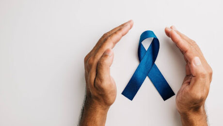 direitos-previdenciarios-pacientes-cancer-de-prostata Mãos em posição de proteção ao redor de um laço azul, símbolo da conscientização sobre o câncer de próstata.