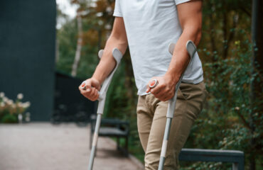 Auxílio-doença e auxílio-acidente: quando é possível acumular benefícios Homem utilizando muletas após lesão, representando situações que podem gerar auxílio-doença ou auxílio-acidente no INSS.