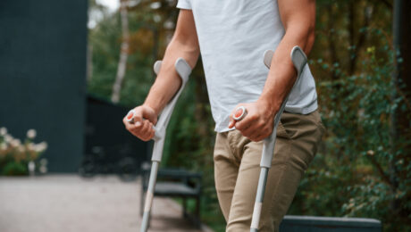 Auxílio-doença e auxílio-acidente: quando é possível acumular benefícios Homem utilizando muletas após lesão, representando situações que podem gerar auxílio-doença ou auxílio-acidente no INSS.