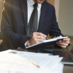 Advogado de terno analisando documentos e fazendo anotações em um escritório, representando a preparação de recurso no INSS.