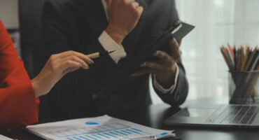 Gestores analisando gráficos financeiros e indicadores de inadimplência em um ambiente corporativo sob orientação jurídica.