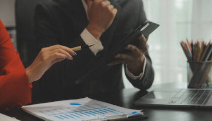 Gestores analisando gráficos financeiros e indicadores de inadimplência em um ambiente corporativo sob orientação jurídica.