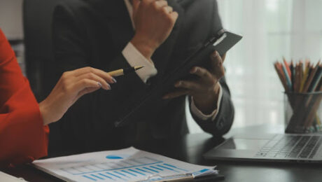 Gestores analisando gráficos financeiros e indicadores de inadimplência em um ambiente corporativo sob orientação jurídica.