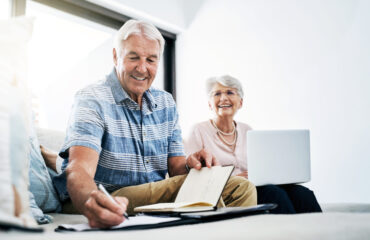 Casal de idosos analisando documentos e usando notebook para planejar aposentadoria pelo INSS em 2026