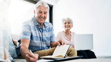 Casal de idosos analisando documentos e usando notebook para planejar aposentadoria pelo INSS em 2026