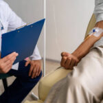 Médico com prancheta atendendo paciente em tratamento renal, explicando se quem tem nefropatia grave pode se aposentar por invalidez.