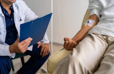 Médico com prancheta atendendo paciente em tratamento renal, explicando se quem tem nefropatia grave pode se aposentar por invalidez.