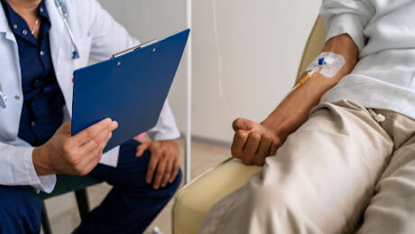 Médico com prancheta atendendo paciente em tratamento renal, explicando se quem tem nefropatia grave pode se aposentar por invalidez.