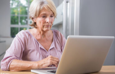 Consulta da tabela do INSS 2026 pela internet Idosa consultando informações da tabela do INSS 2026 no notebook em casa