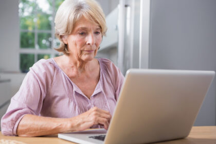 Idosa consultando informações da tabela do INSS 2026 no notebook em casa