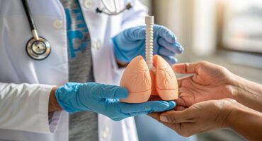 Médico segurando modelo de pulmão durante atendimento sobre tuberculose ativa e benefícios no INSS