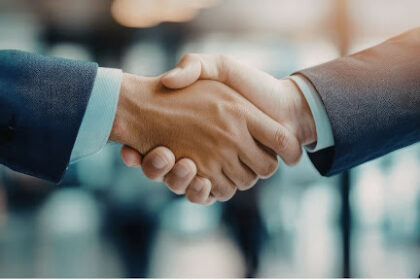 Aperto de mãos entre dois profissionais em traje formal, simbolizando a formalização de um tipo societário e o fechamento de um acordo empresarial.